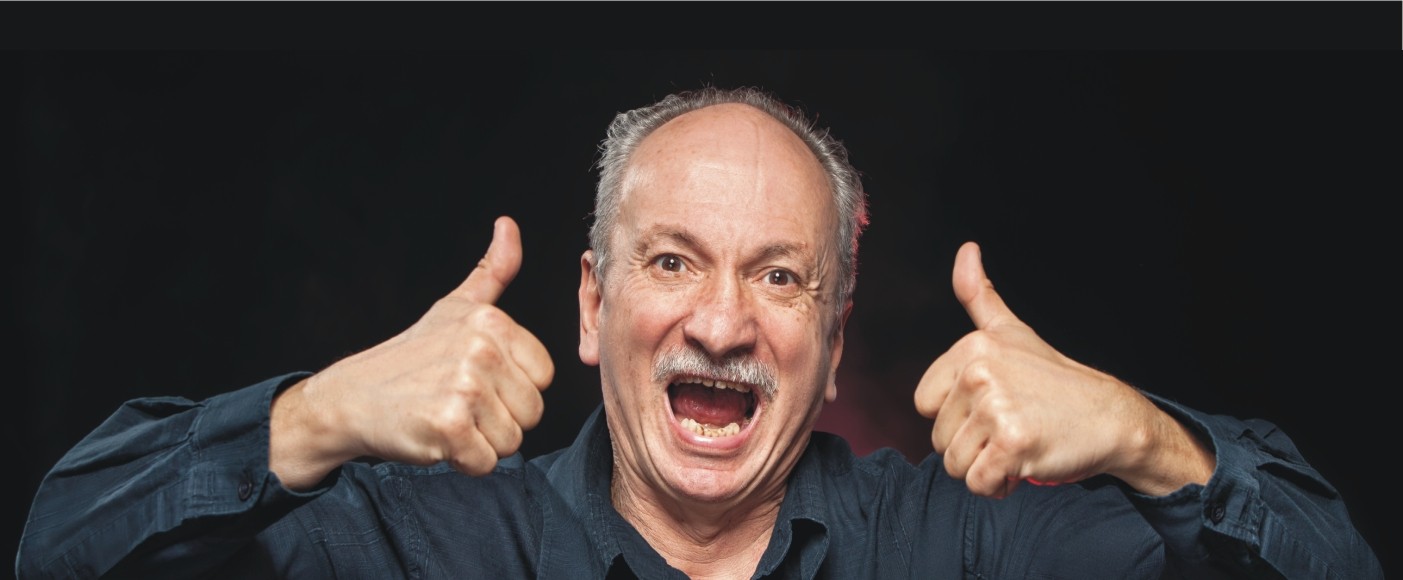 Ein Mann lacht und hebt beide Daumen